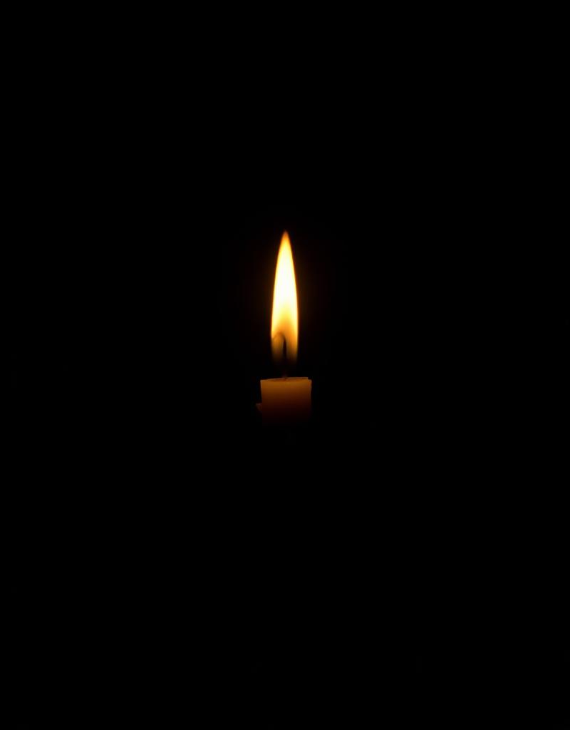 A single candle flame in the dark